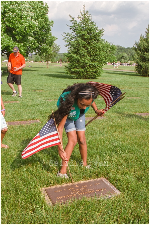 Girl Scouts placing American flags on graves on military for Memorial Day at Brigadier General Doyle Cemetary 