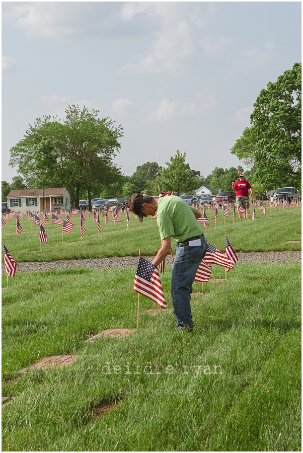 Girl Scouts placing American flags on graves on military for Memorial Day at Brigadier General Doyle Cemetary 