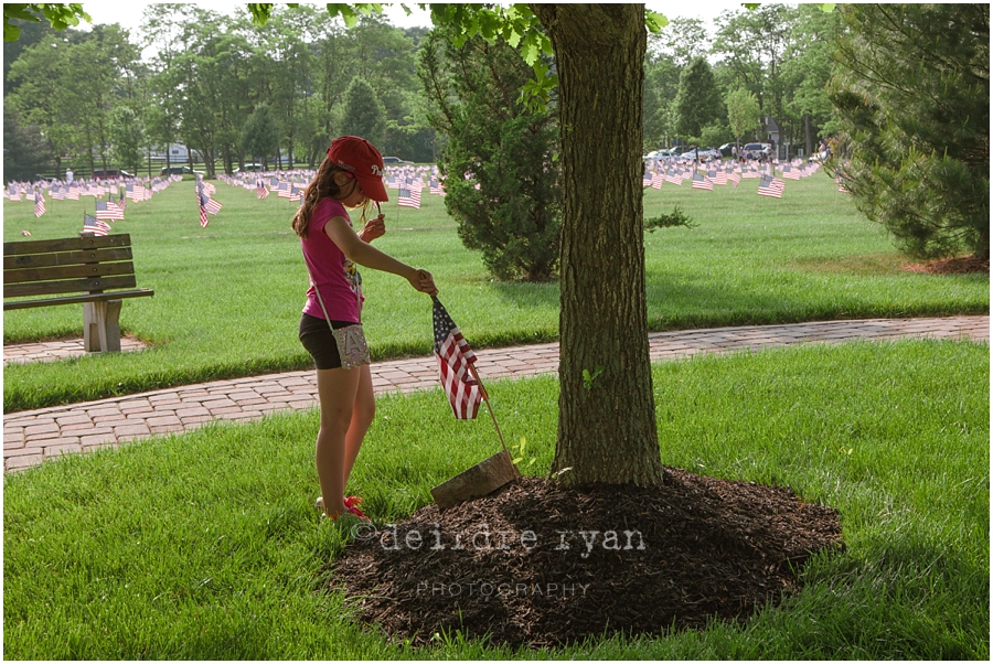 Girl Scouts placing American flags on graves on military for Memorial Day at Brigadier General Doyle Cemetary 