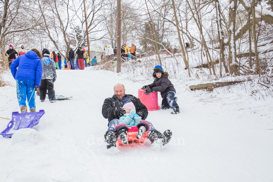 Children sledding down a hill on a snow day from school. Photo by Deirdre Ryan Photography